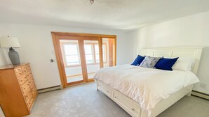 Un dormitorio con cama, cómoda y puerta corrediza de vidrio que da a un área exterior.