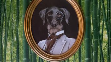 Un portrait encadré d’un chien portant un costume, avec un fond de bambous.