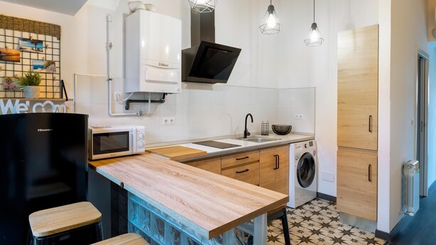Een moderne keuken met een centraal eiland, een ingebouwde wasmachine en een magnetron.