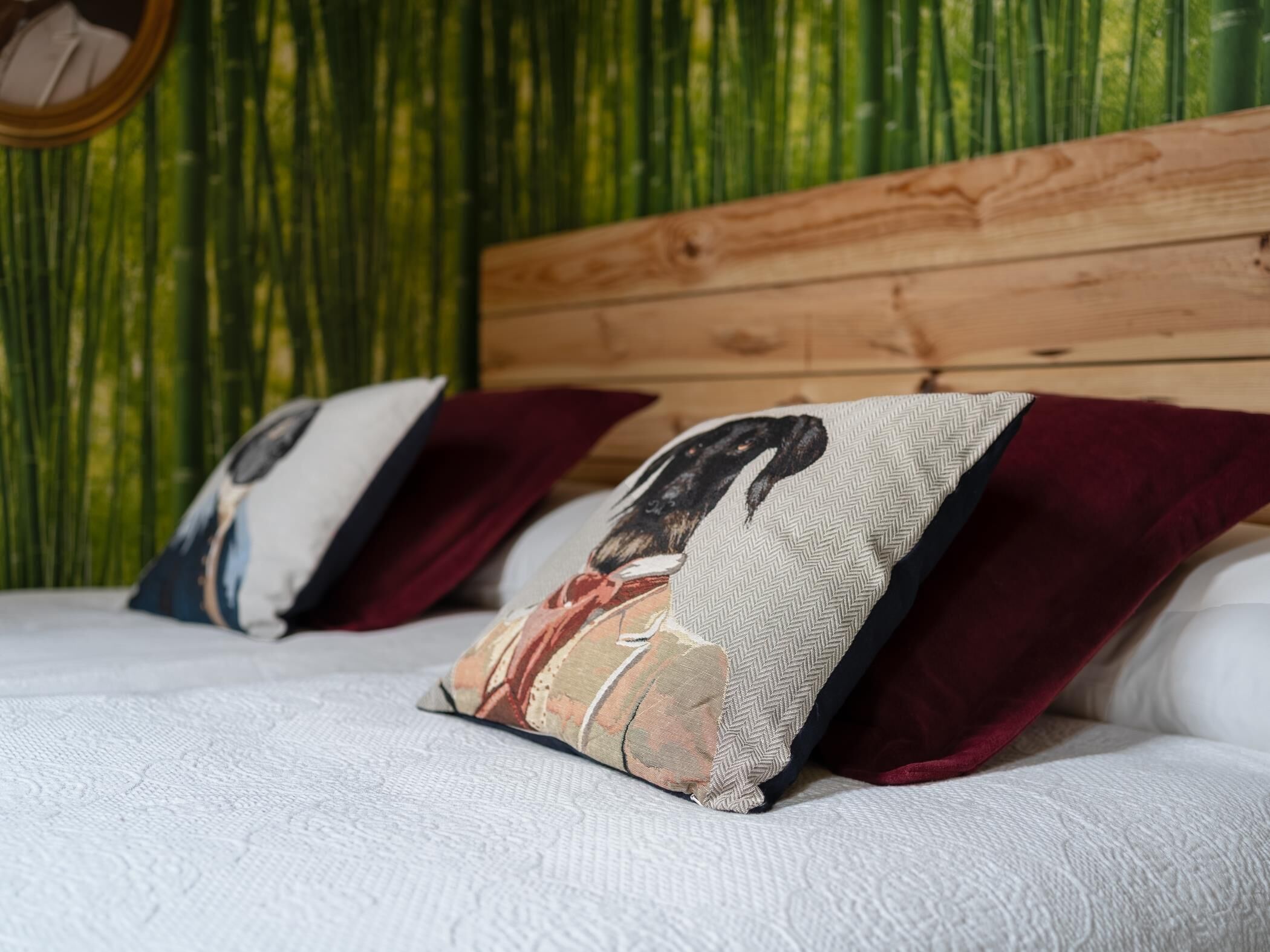 A bed with white bedding and two decorative pillows against a wooden headboard.