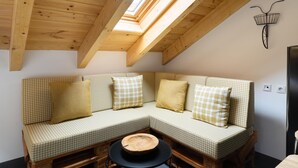 Een gezellig loft slaapkamer met een geruit bankje, een ronde houten tafel en een dakraam.