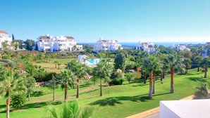 A coastal residential area with white houses, palm trees, and a clear blue sky. - 2288 Luxury Penthouse with Private Rooftop Pool (Estepona)