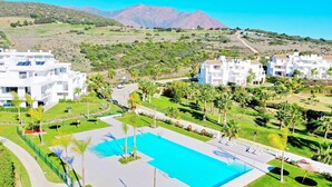 A resort with a swimming pool, white buildings, and a mountainous backdrop. - 2288 Luxury Penthouse with Private Rooftop Pool (Estepona)