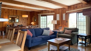 A cozy wooden-furnished living room with a blue sofa, a green armchair, and a wooden coffee table. - Private Mountain Getaway at Dogwood Hill (Rosman)