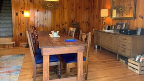 A wooden dining room with a table, chairs, and a bench. There is a staircase in the background, and a cabinet with items on top. - Private Mountain Getaway at Dogwood Hill (Rosman)