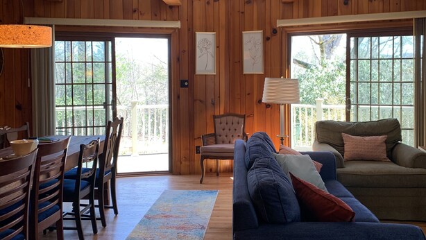A wooden-paneled room with a dining table, chairs, a sofa, and a window. - Private Mountain Getaway at Dogwood Hill (Rosman)