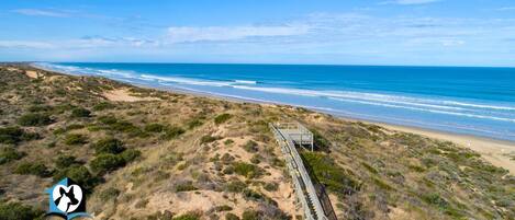 A coastal landscape with a wooden boardwalk leading to a beach.
