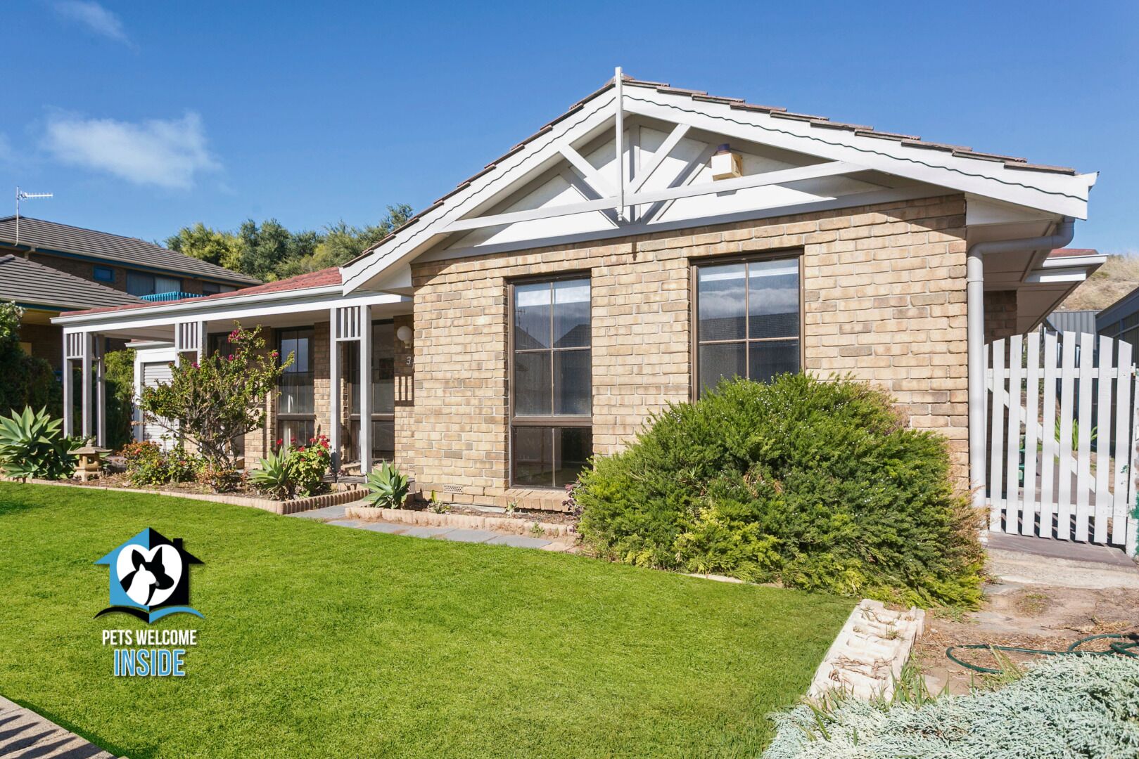 A two-story house with a brick facade, large windows, and a well-maintained lawn.