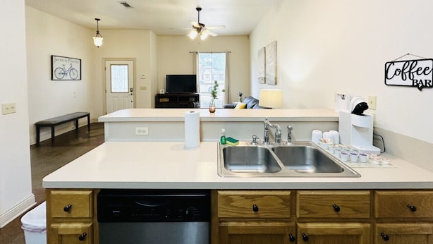 A modern kitchen with a central island, double sinks, and wooden cabinets.