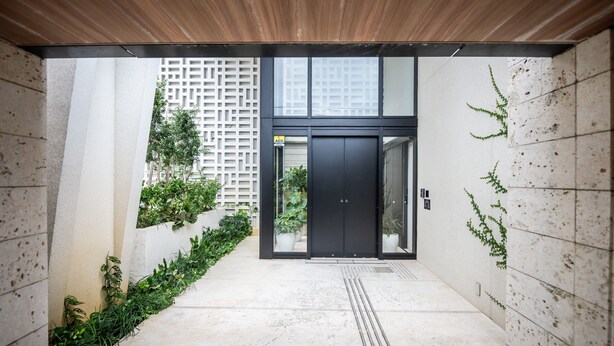 A modern building entrance with a black door, a wooden ceiling, and a concrete floor. - Tabino Hotel lit Miyakojima (Miyakojima)