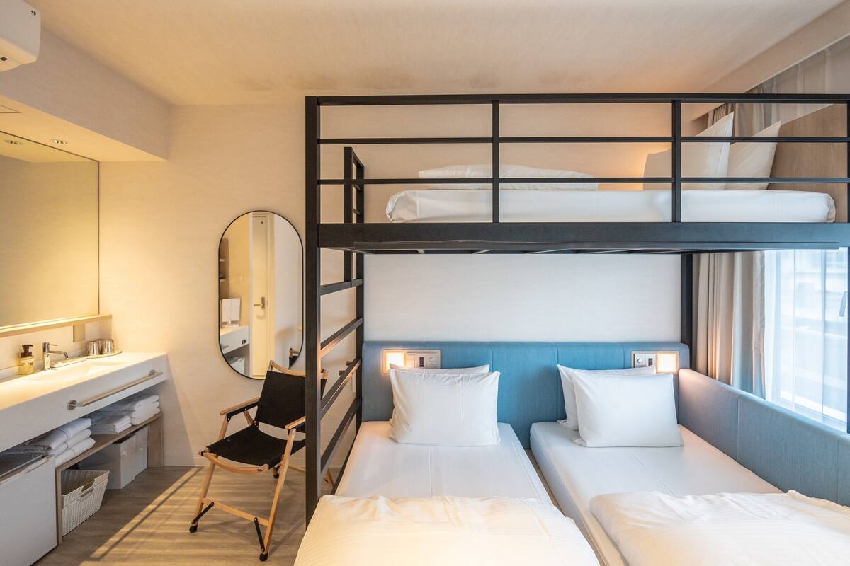A bunk bed room with a desk, chair, and a mirror.