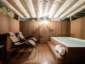 Un área de spa de madera con un jacuzzi y sillones reclinables.