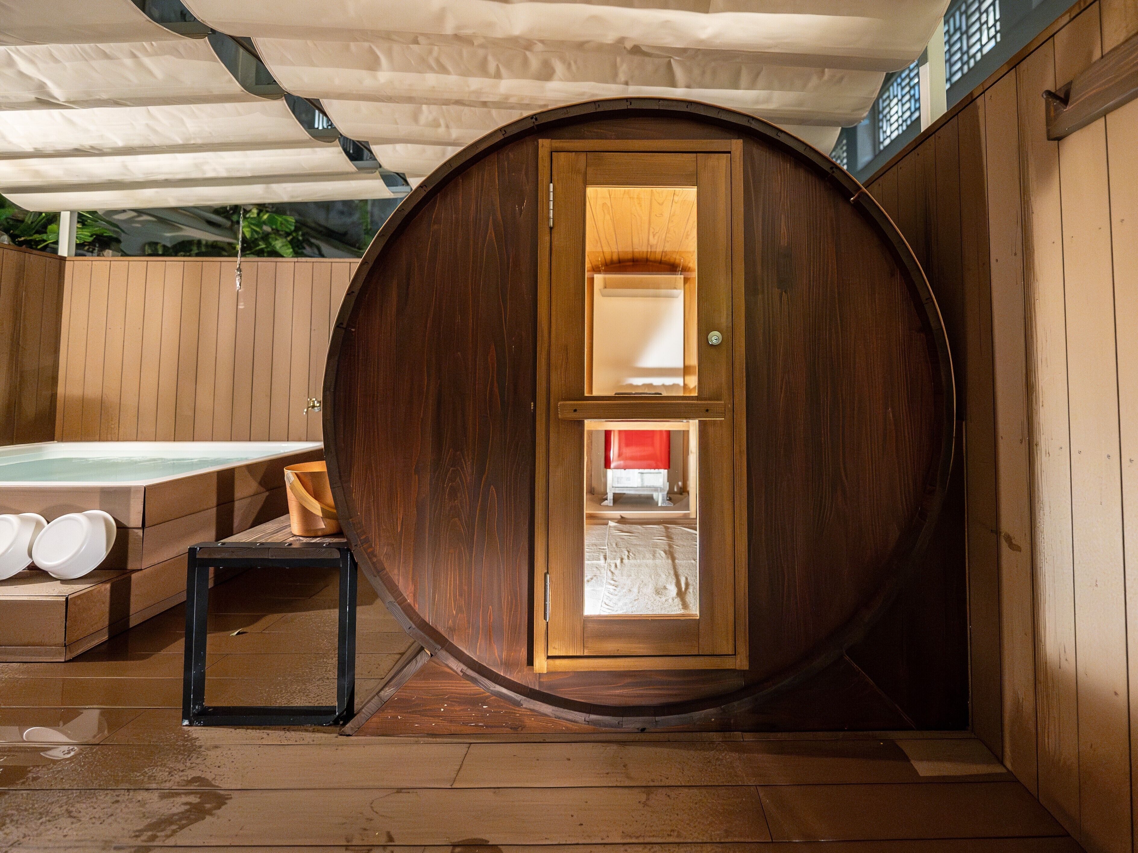 A wooden barrel-shaped room with a hot tub and a small table.
