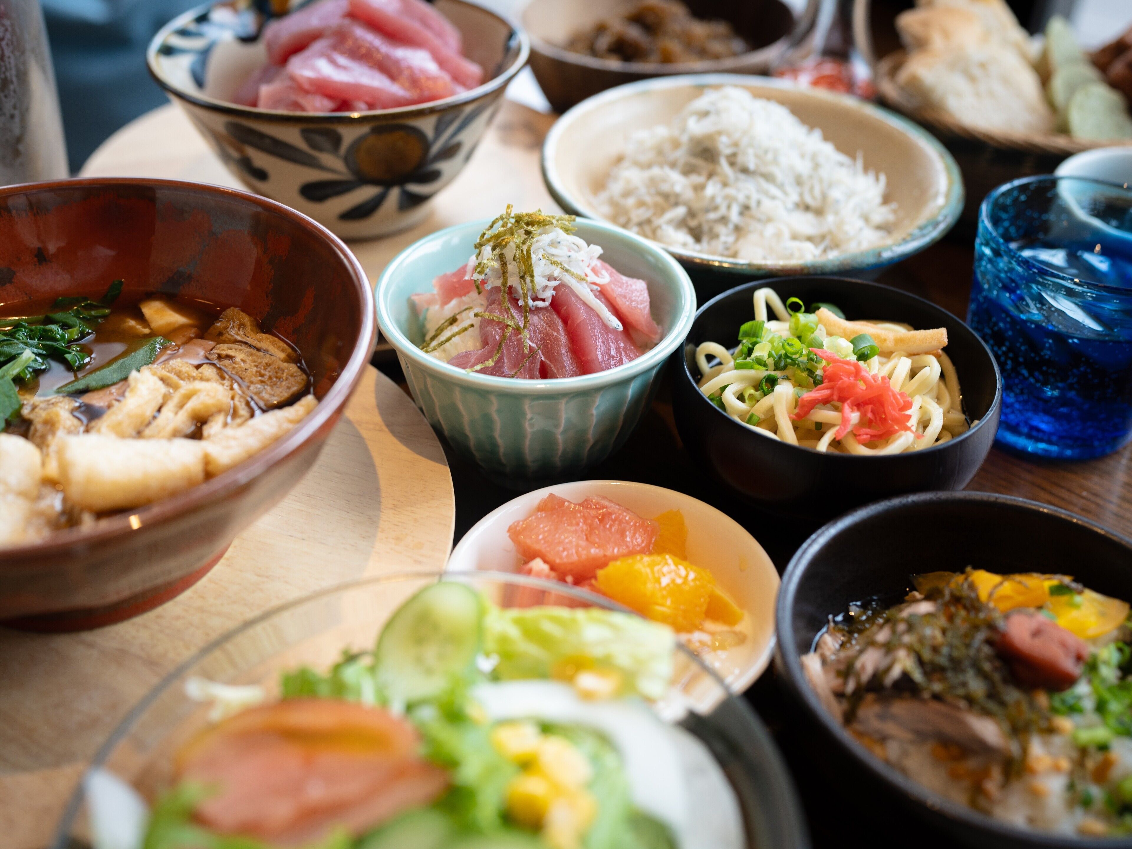 Diversos pratos, incluindo sushi, arroz e macarrão, indicando um ambiente para refeições japonesas.