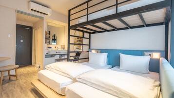 A hotel room with a bunk bed, a desk with a chair, a small kitchenette, and a bathroom.