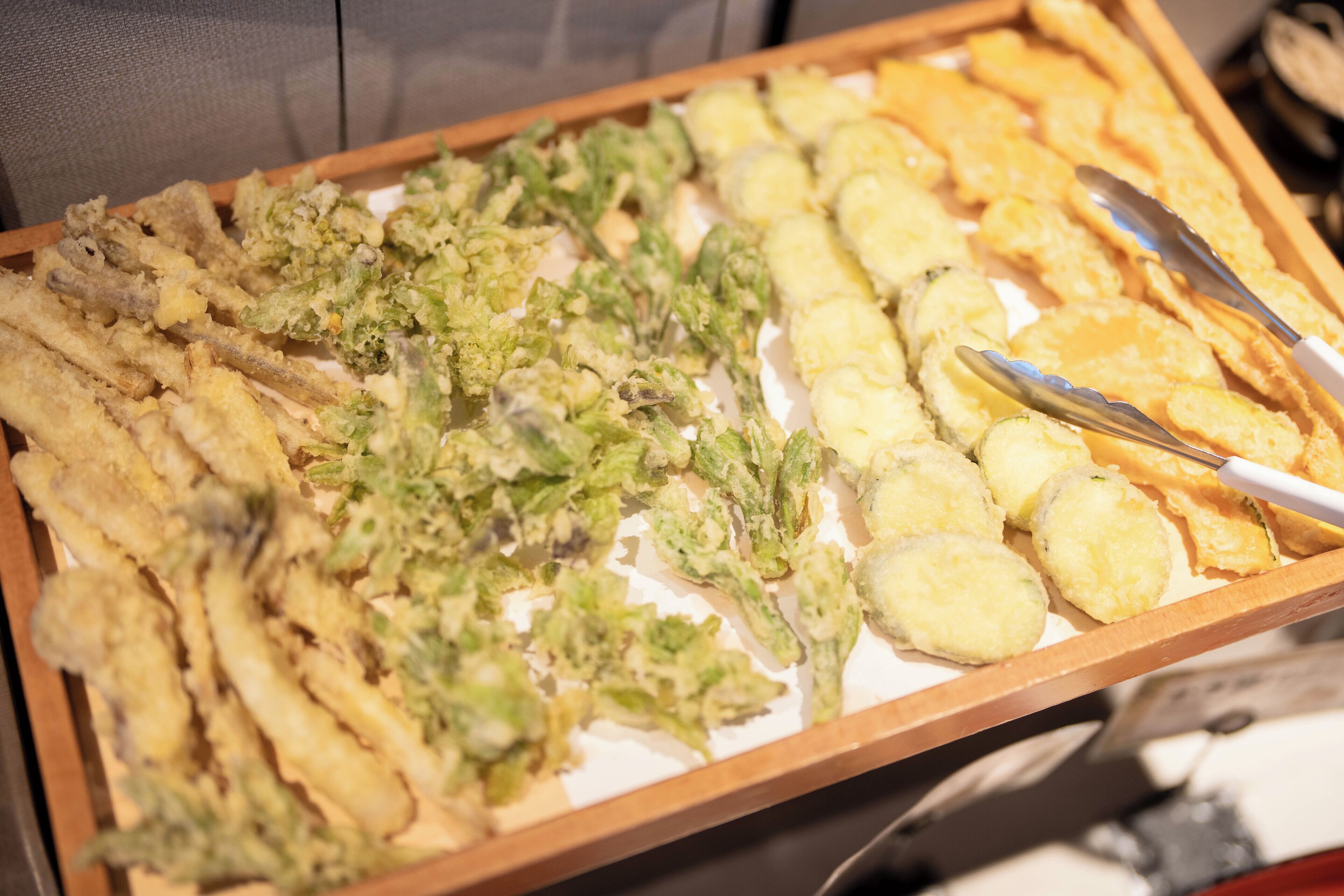 A tray of various fried foods including tempura, green vegetables, and shrimp.