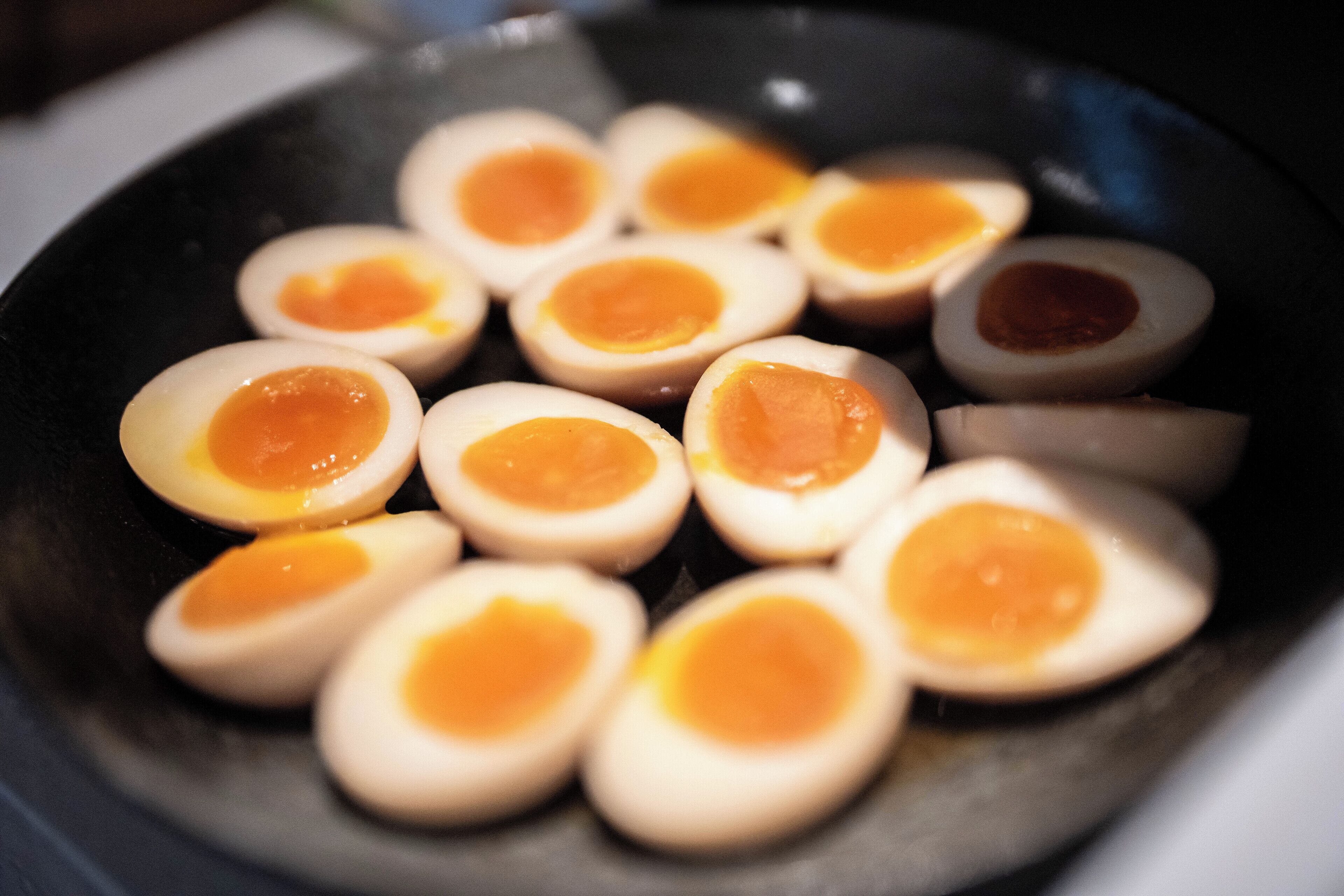 A pan with several halves of boiled eggs.