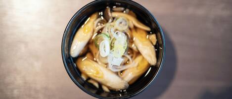 A bowl of soup with noodles and sliced green onions.