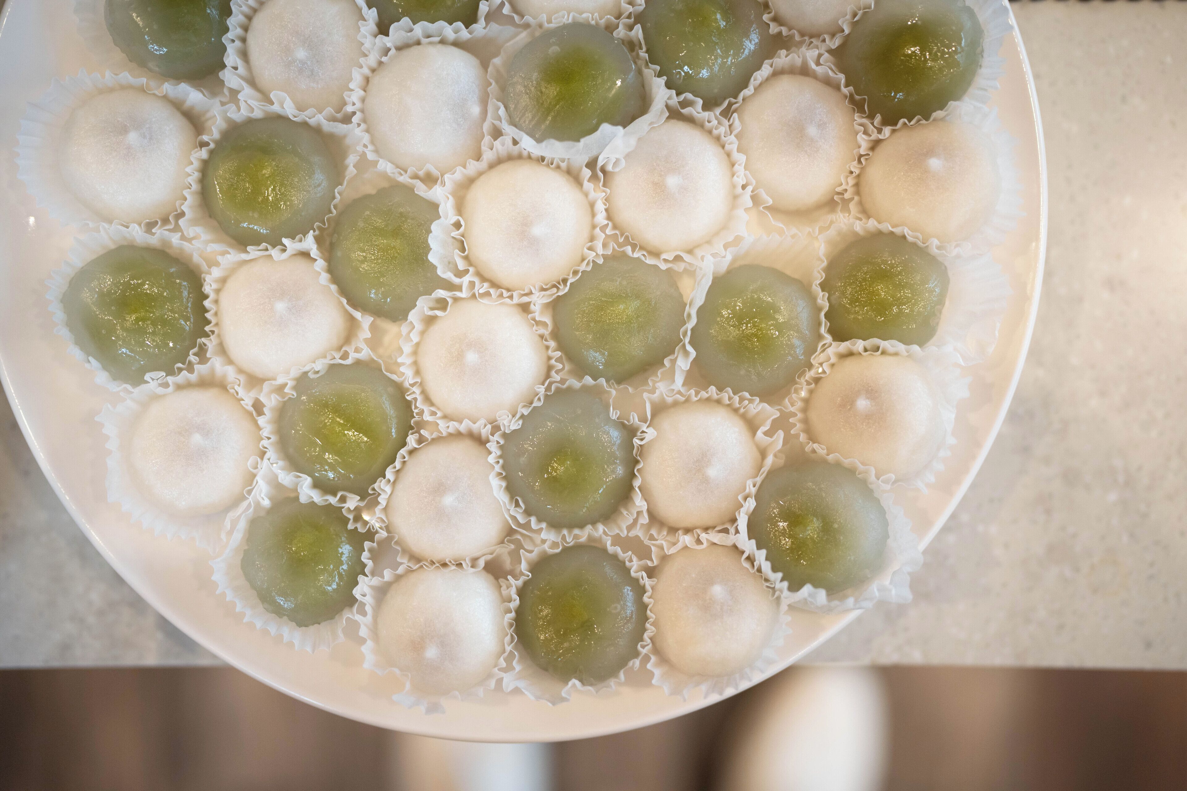 A plate of round, translucent sweets in white and green wrappers.