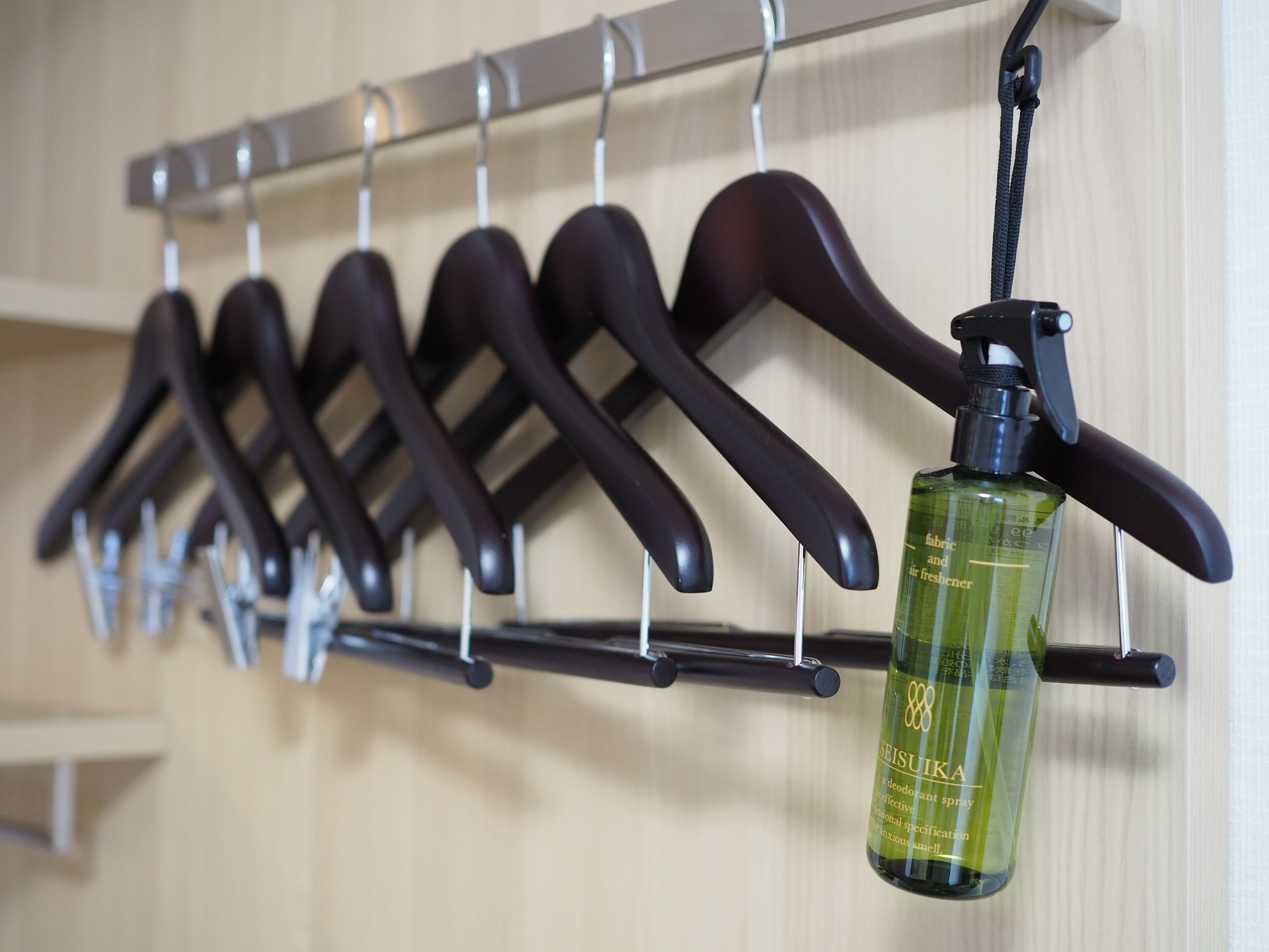 A rack with several black hangers and a bottle of Seisuiya deodorant hanging from it.