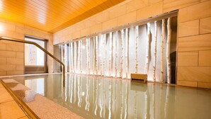 Una piscina interior con pared de cristal y barandilla de metal.