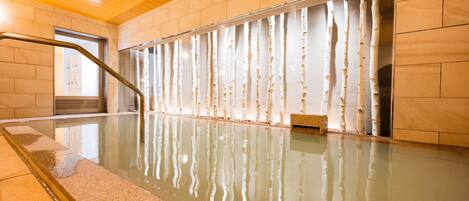 An indoor swimming pool with a glass wall and a metal railing.