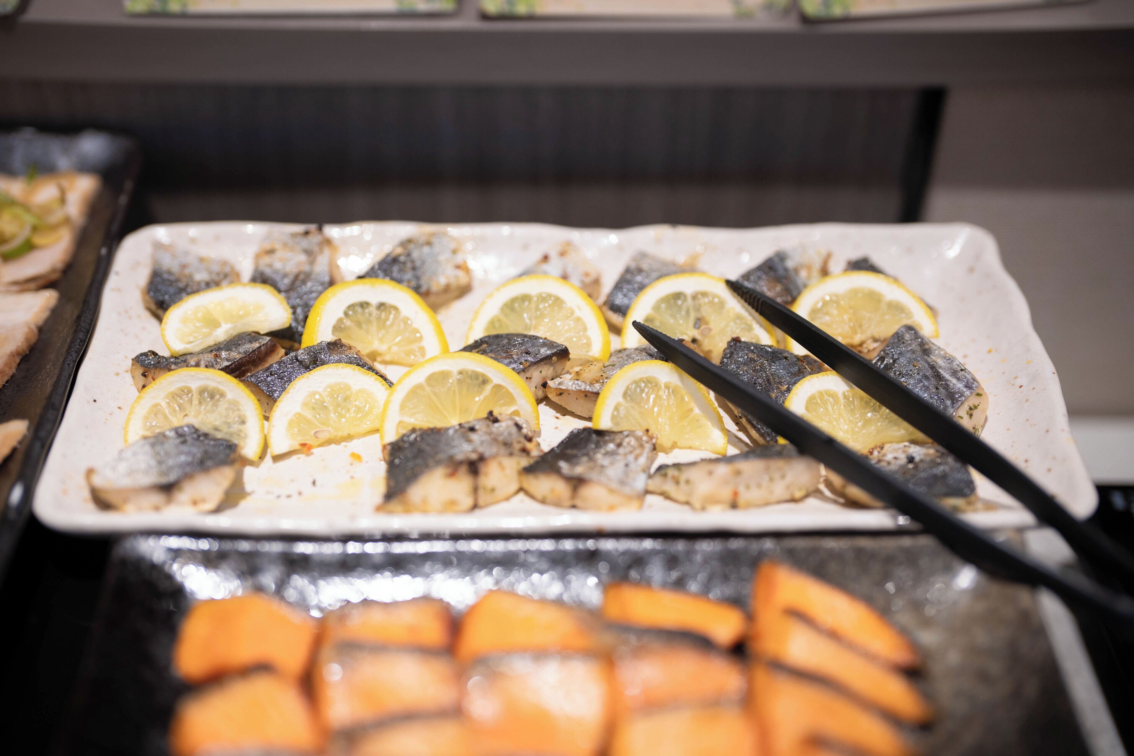 A tray of grilled fish garnished with lemon slices.