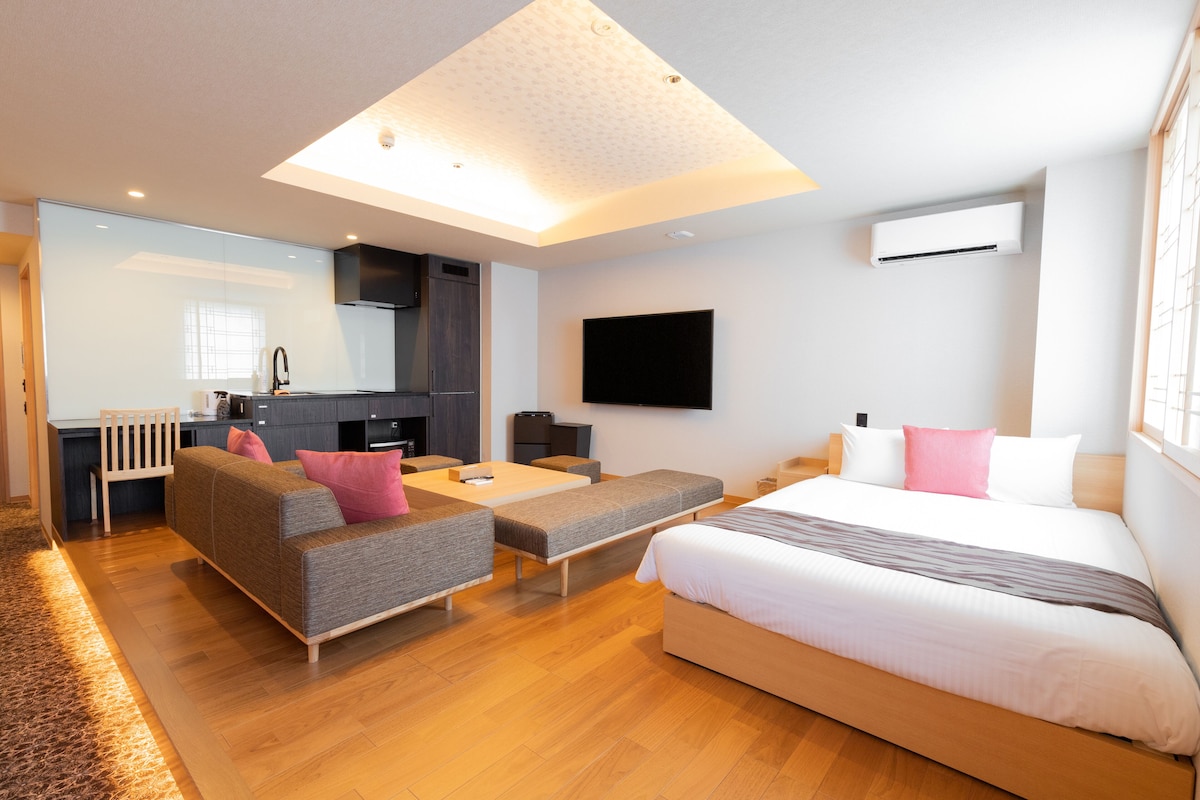 Ein modernes Hotelzimmer mit Sofa, Bett, Essbereich und einer Küche.