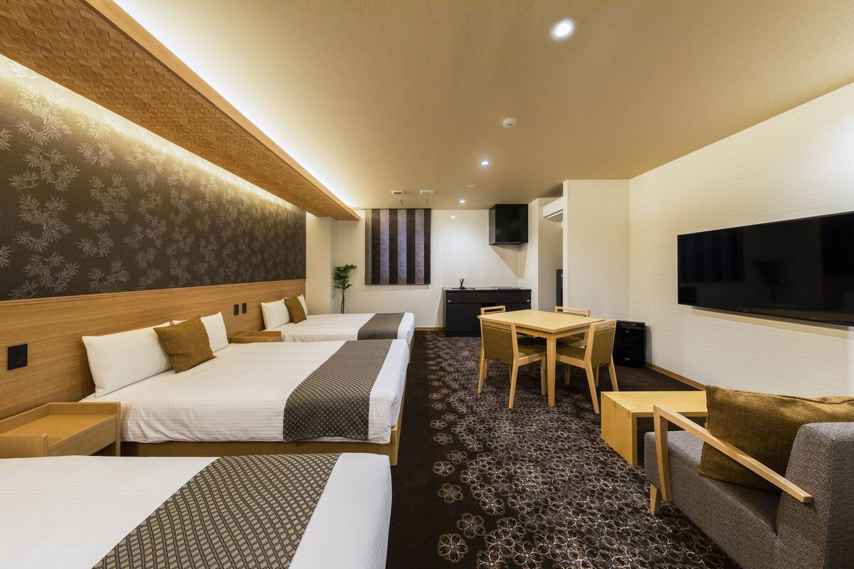 Une chambre d’hôtel avec deux lits, une télévision, un bureau et un canapé.