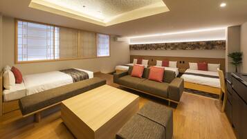 A modern hotel room with a large bed, a sofa, a bench, and a small table. There is a large window with a view of the outside.