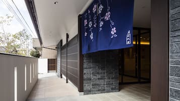 A corridor with a blue floral curtain, a stone wall, and a tiled floor.