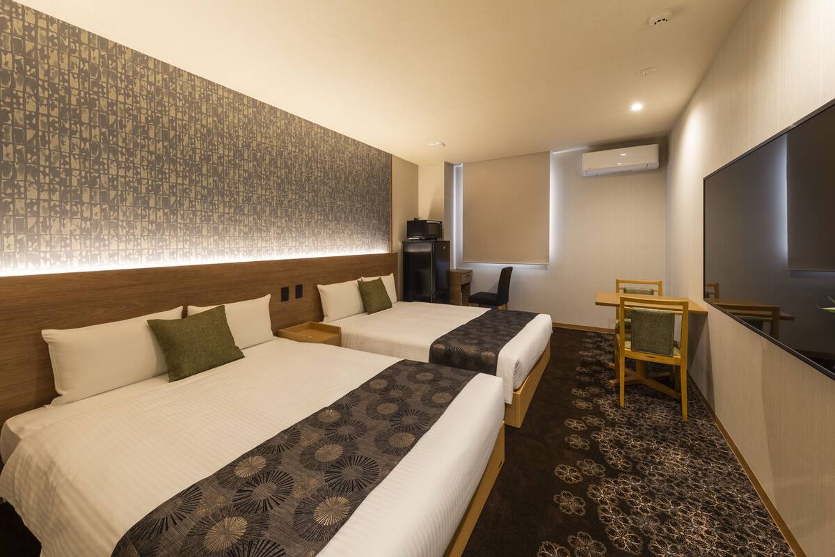 Une chambre d’hôtel avec deux lits, une télévision, un bureau et une chaise.
