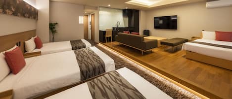 Et moderne hotelværelse med tre senge, en sofa, et fjernsyn og et tekøkken.