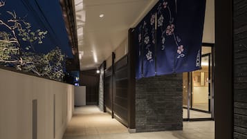 A corridor with a tiled floor, a wall with a dark brick pattern, and a blue decorative hanging.