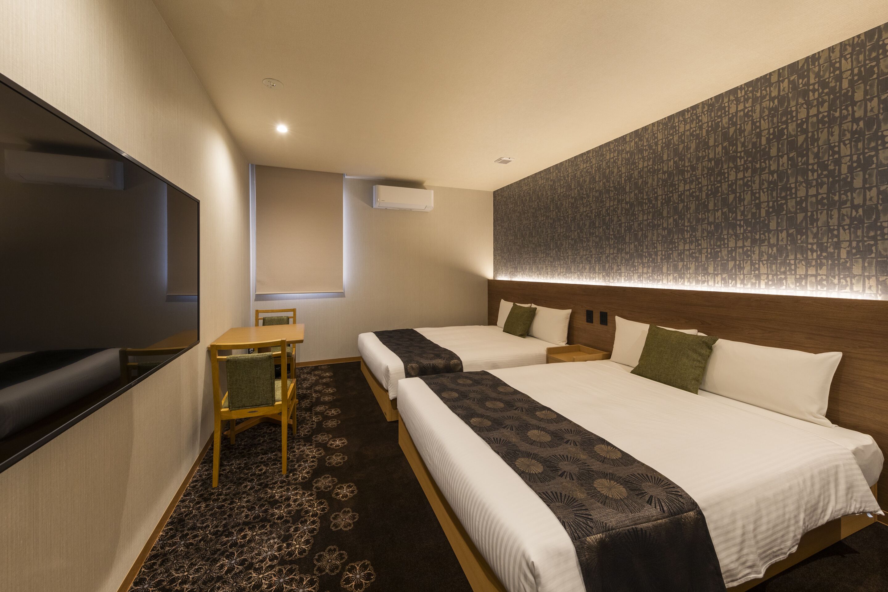A hotel room with two beds, a desk, and a TV.