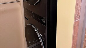 A laundry room with a wall-mounted dryer and a door with a towel rack. - Peaceful Kona Retreat—Steps to Magic Sands Beach · Ocean View · King Beds · AC! (Kailua-Kona)