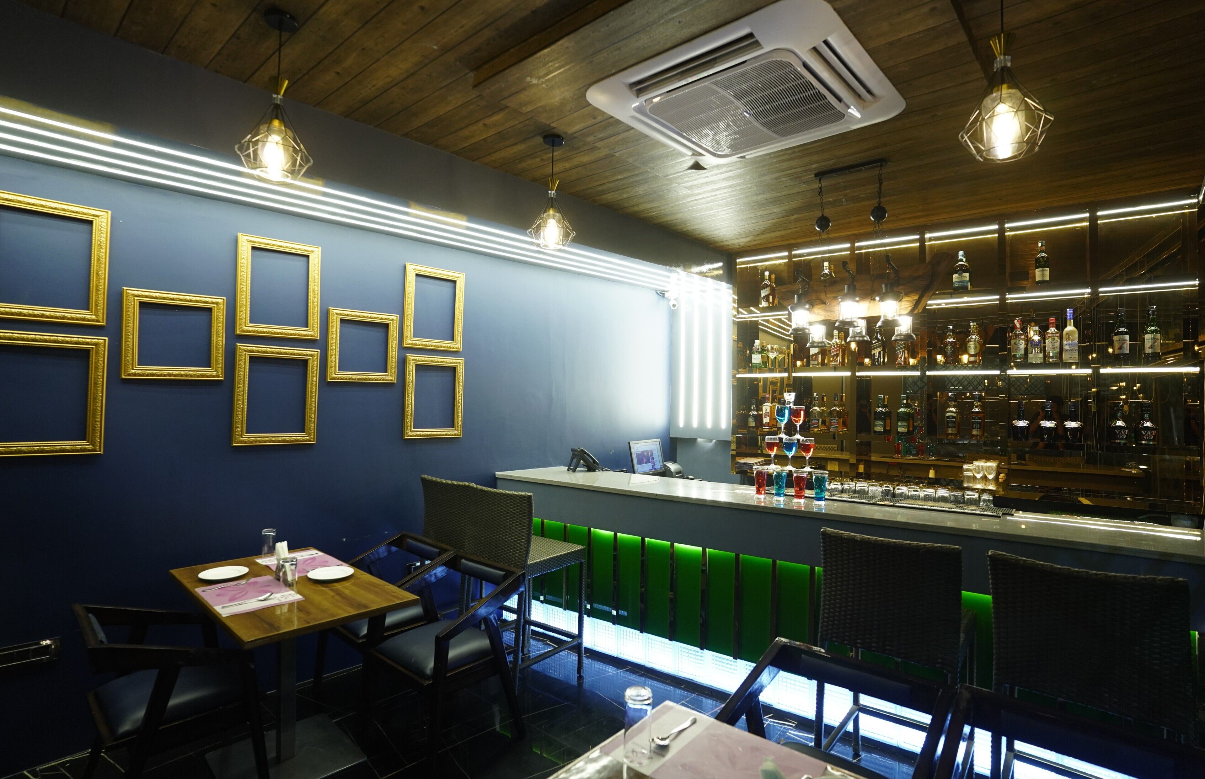 A bar area with a counter, seating, and a wall with framed pictures.