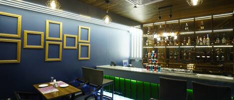 A bar area with a counter, seating, and a wall with framed pictures.