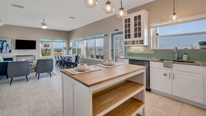 Une cuisine moderne avec des meubles blancs, un îlot central en bois et des luminaires suspendus.