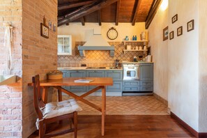 Une cuisine avec une table en bois, un mur en briques et un sol carrelé.