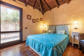 Une chambre à coucher avec un grand lit, une fenêtre, une table de chevet et une chaise.
