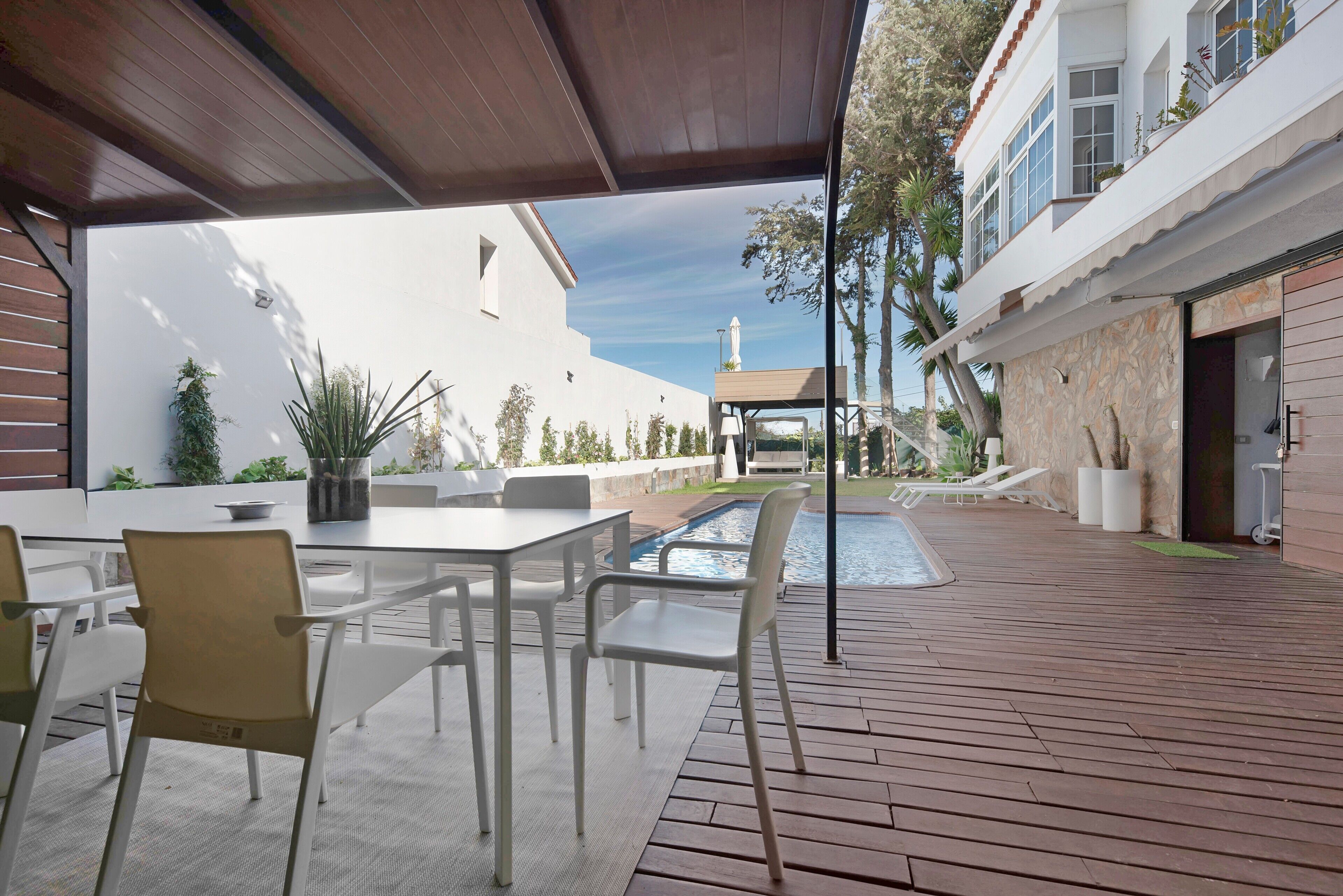 An outdoor patio with a pool, seating area, and a view of a building with a statue.