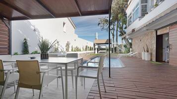 An outdoor patio with a pool, seating area, and a view of a building with a statue.