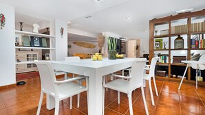 A modern kitchen with white cabinetry, a dining table with chairs, and a built-in bookshelf. - "Loft la Matanza" with Sea View, Mountain View, Pool, Terrace & Garden (La Matanza)