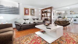 A modern living room with a sofa, coffee table, and a bookshelf. - "Loft la Matanza" with Sea View, Mountain View, Pool, Terrace & Garden (La Matanza)