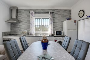 Eine moderne Küche mit Esstisch, Stühlen, einer Vase und einer Uhr an der Wand.