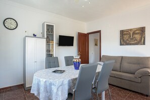 Ein Essbereich mit Tisch, Stühlen, einem Fernseher, einer Couch und einem Schrank.