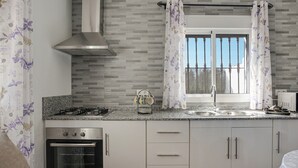 Una cocina moderna con estufa a gas, horno, armarios de acero inoxidable y una ventana con cortinas.