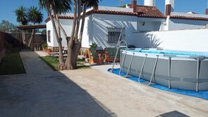 Una propiedad residencial con piscina, palmeras y un patio cubierto.