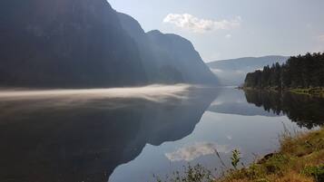 A calm lake with mountains in the background and a clear sky.